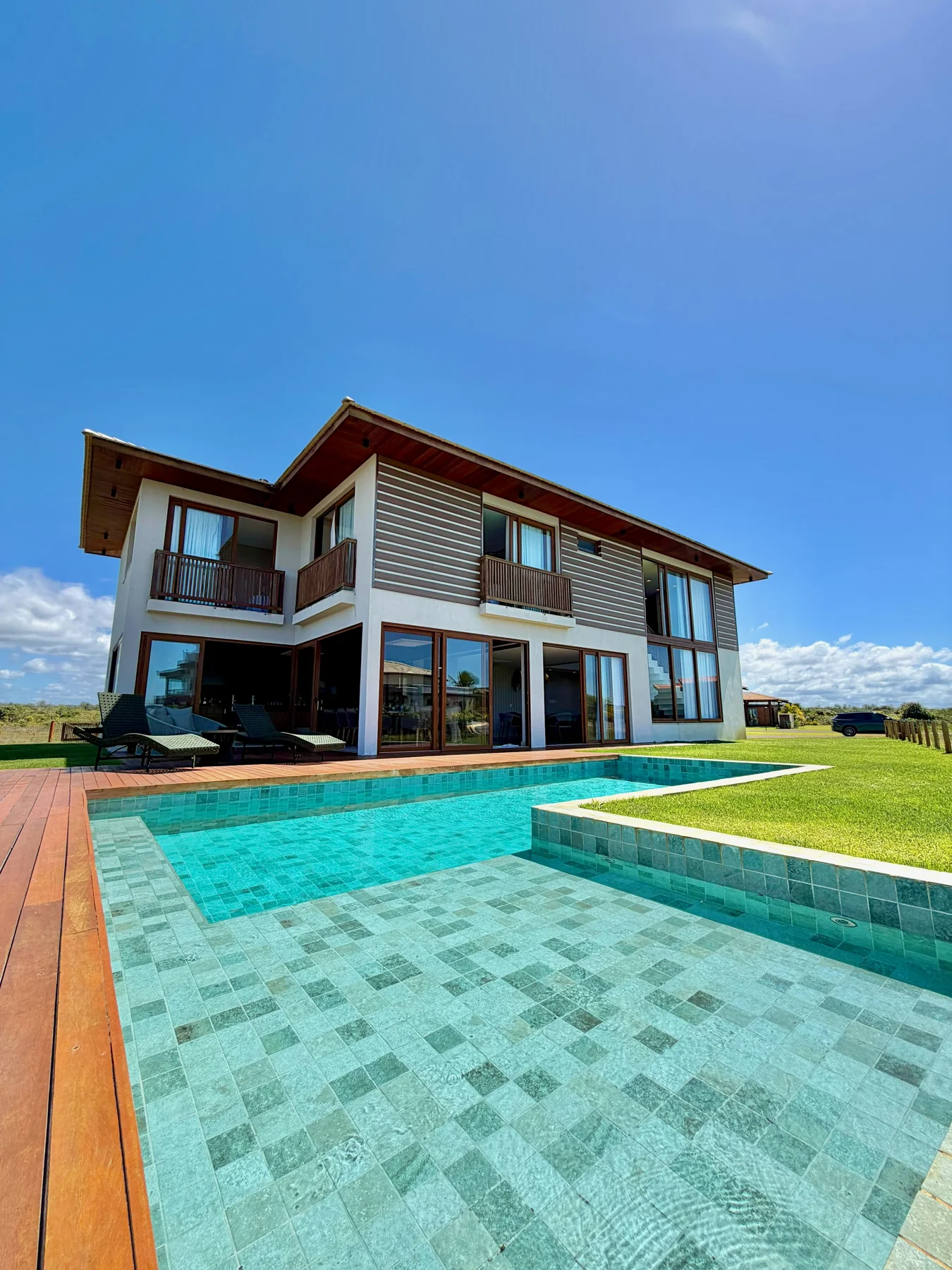 Piscina com deck molhado e fachada da casa no Iberostar